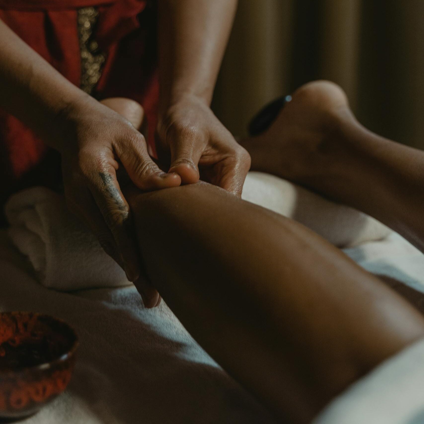 Close-up of hands giving a therapeutic leg massage at a spa, promoting relaxation and wellness.