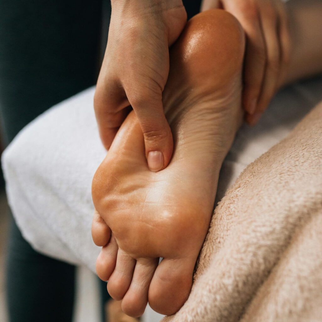 Hands massaging a foot to provide relaxation and promote wellness indoors.